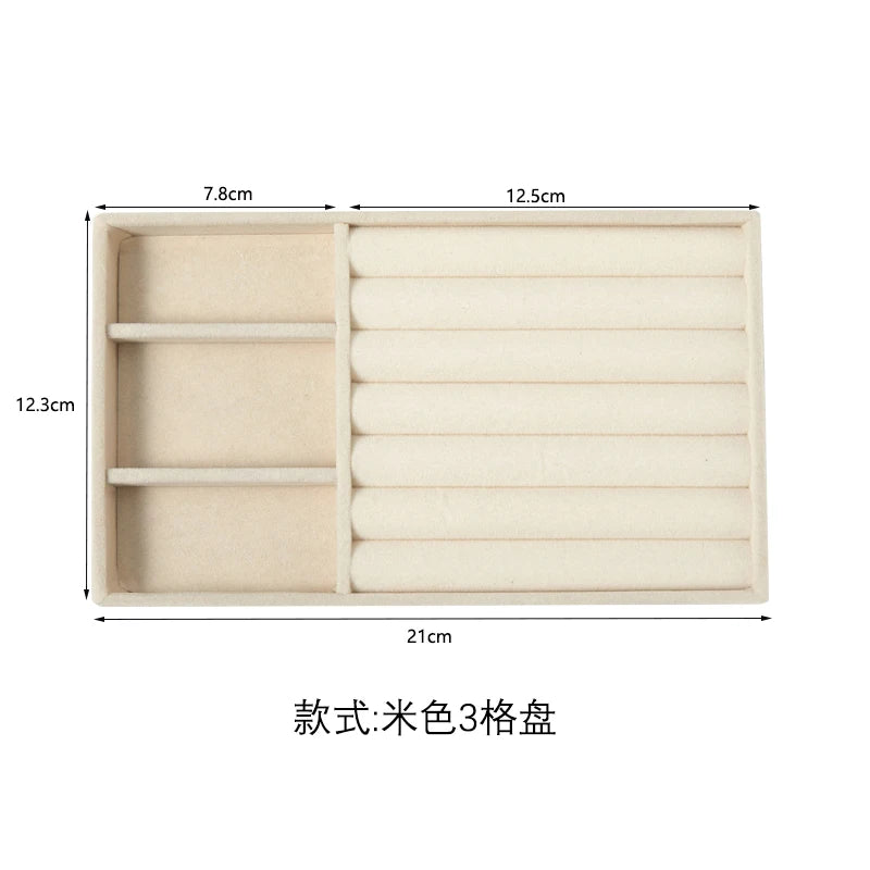 A beige velvet jewelry organizer tray with three detachable compartments.