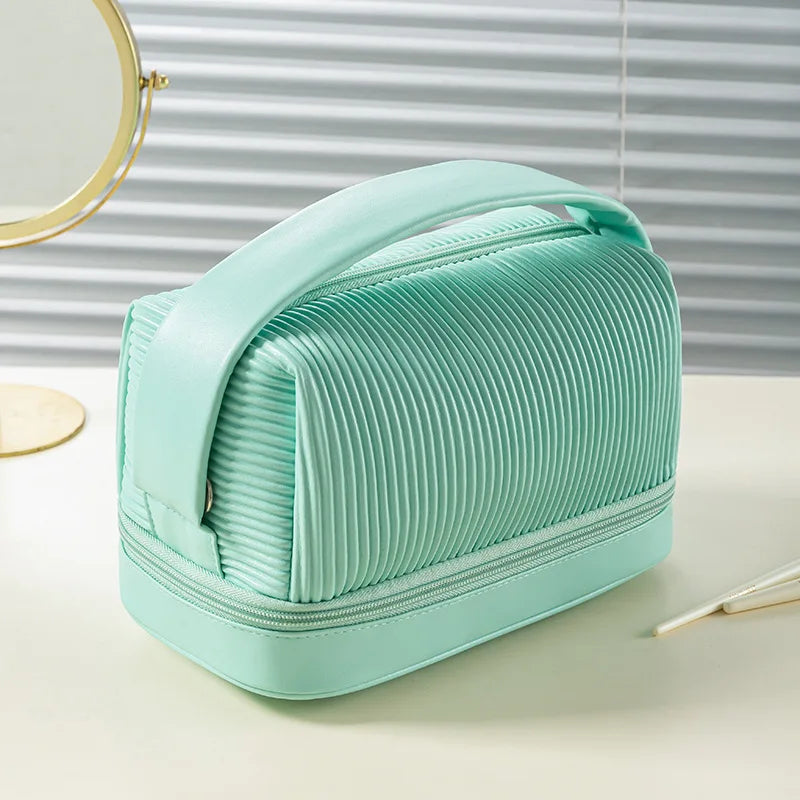 A mint green, accordion-style PU leather makeup bag is shown on a white surface next to a circular mirror.