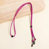 A purple lanyard with a black clasp and silver-tipped ends is displayed on a light wooden surface.