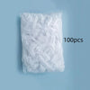 A white plastic bag filled with 100 disposable shower caps for hair protection