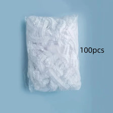 A white plastic bag filled with 100 disposable shower caps for hair protection