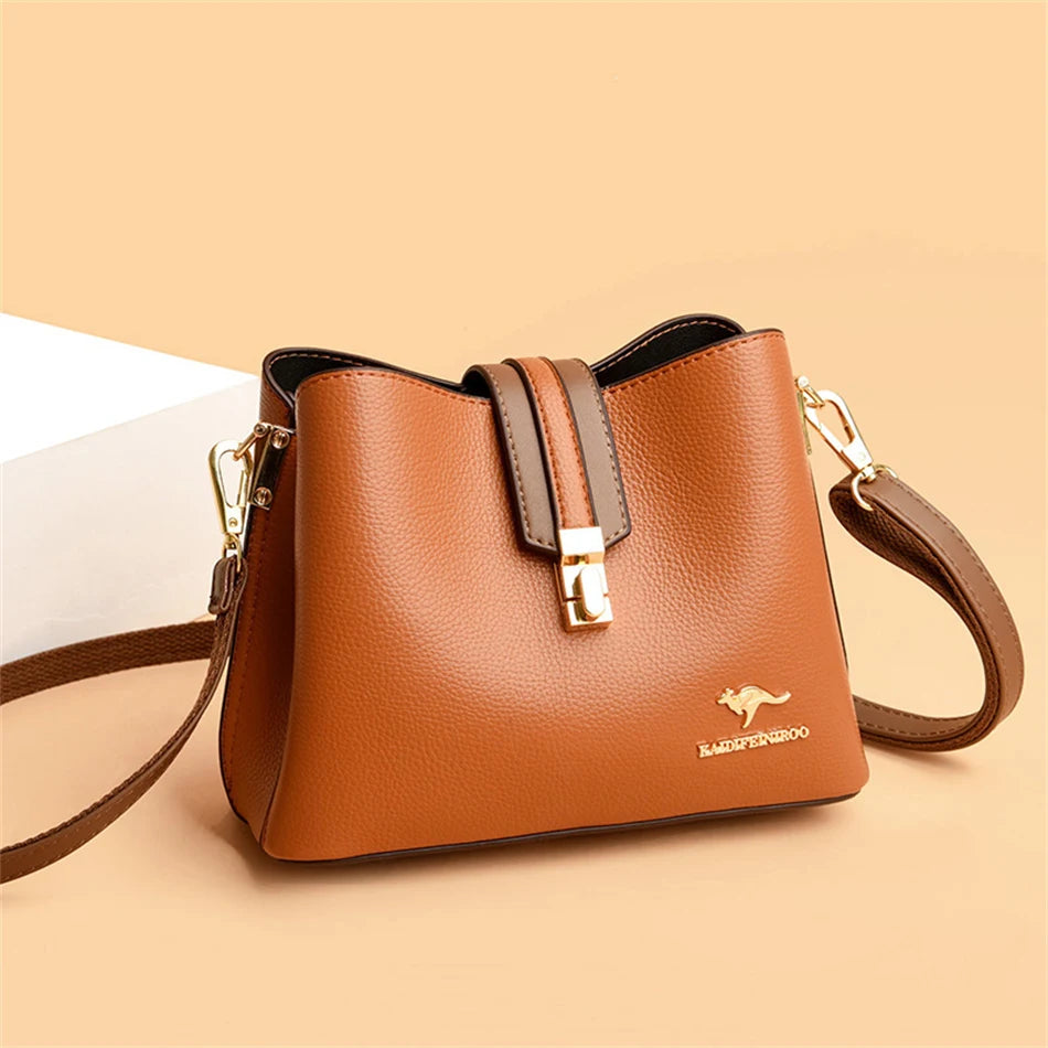 A brown leather shoulder bag with a gold clasp and brown strap resting on a light background.