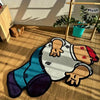 A plush cartoon carpet depicting a character in a white shirt and blue pants lying on a wooden floor.
