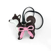 A dark brown and white Shiba Inu PU leather bag charm with a pink braided bow on a black strap.