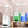 Three clear glass refillable laundry detergent dispenser bottles with white and green labels displayed on a wooden surface.