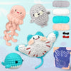 A collection of crocheted animal amigurumi toys including a pink dinosaur, gray monster, white creature, and a blue fish.
