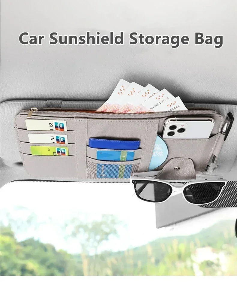 A beige car sunshield storage bag organized with various cards and a smartphone inside.