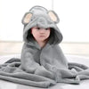 A baby wearing a gray, hooded towel with an elephant design is shown lying down.
