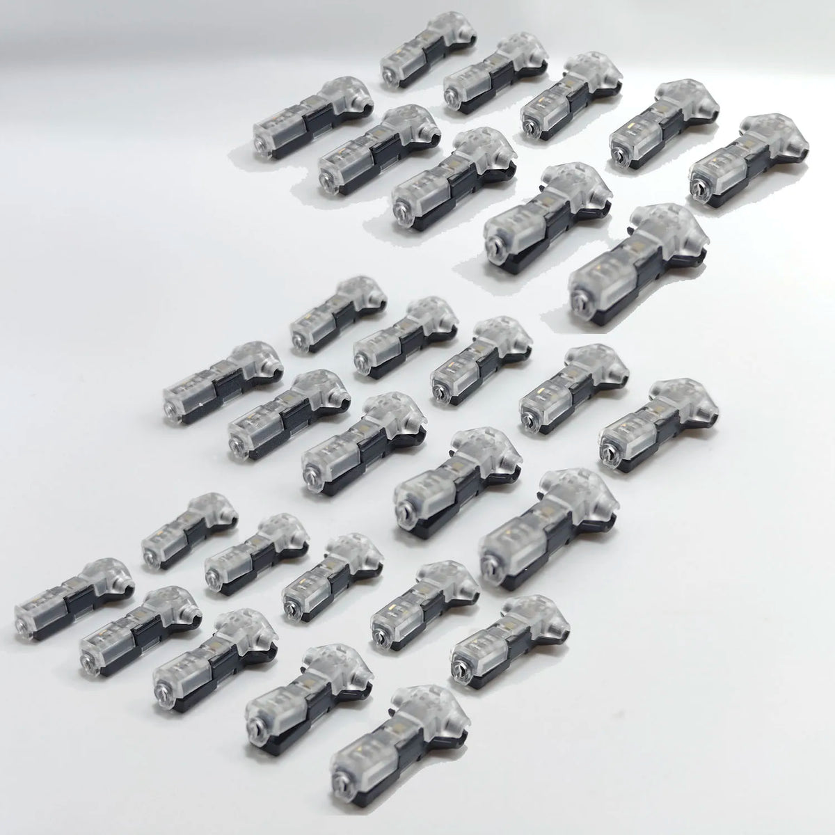 A collection of small, silver-colored quick solderless wire tap connectors arranged in a diagonal line.