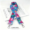 A floral patterned fabric strap in teal pink and blue is displayed next to a white box.