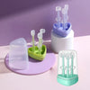 A purple and green silicone toothbrush set with multiple brushes and a tongue cleaner displayed on a white surface.