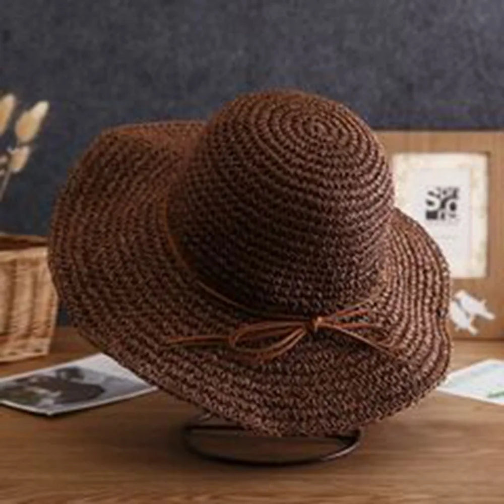 Sombrero de paja tejido marrón de ala ancha sobre una superficie de madera.