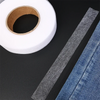 Roll of clear double-sided iron-on adhesive tape next to a piece of denim fabric