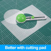 A green circular cutting pad and a white adjustable paper cutter are shown on a green grid surface.