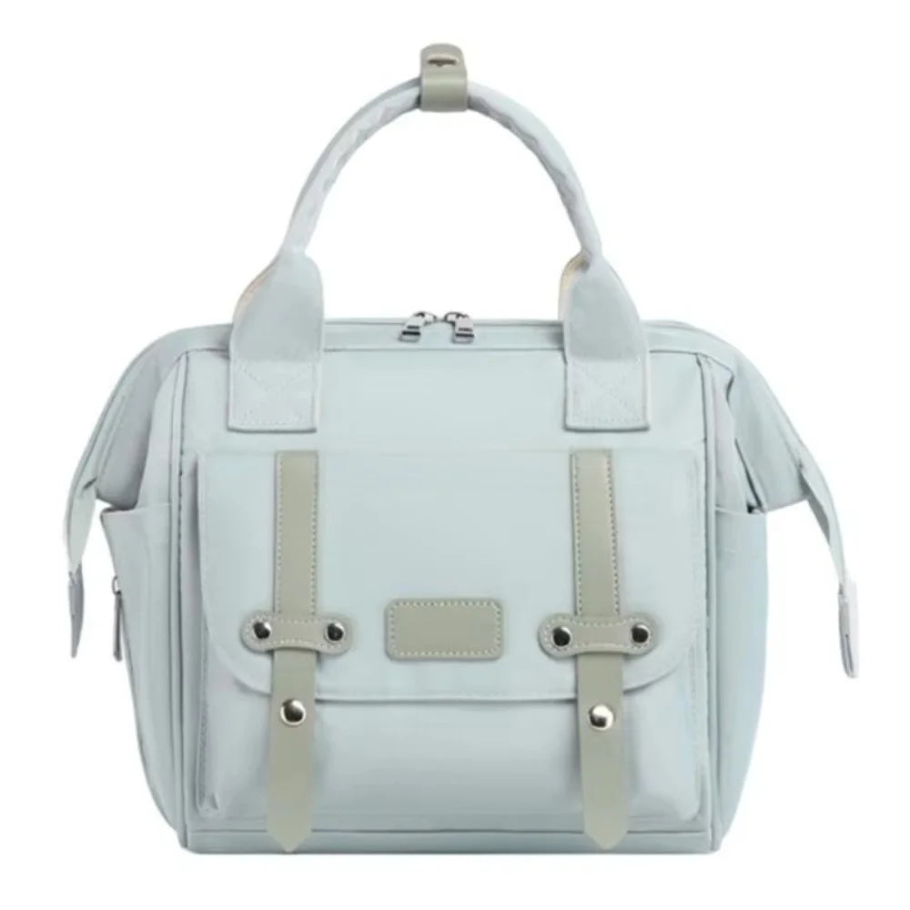 A light blue compact diaper backpack with a beige bottle holder and straps.