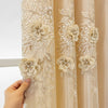 A close-up of a cream embroidered sheer curtain panel with floral patterns.