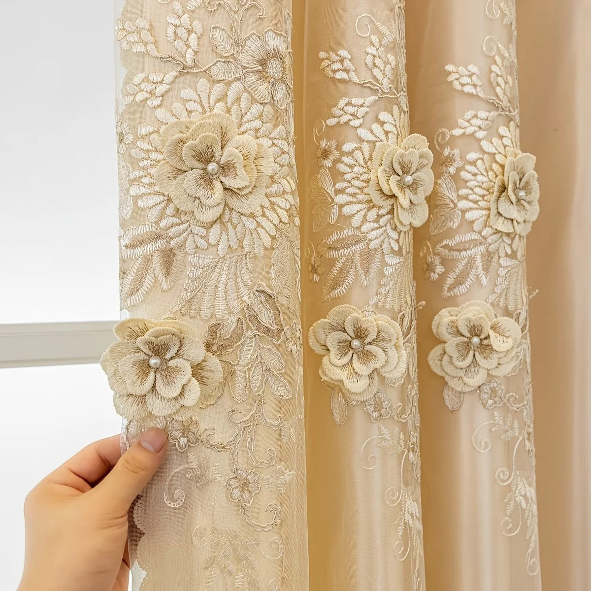 A close-up of a cream embroidered sheer curtain panel with floral patterns.