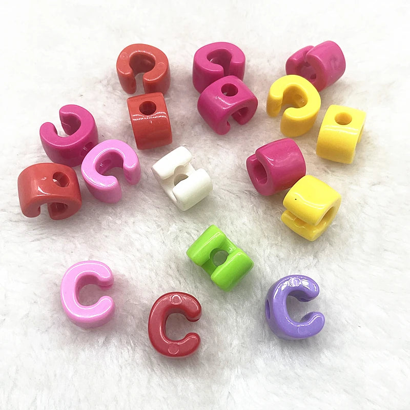 A collection of ten mixed alphabet letter beads in various colors including pink, red, yellow, and purple.