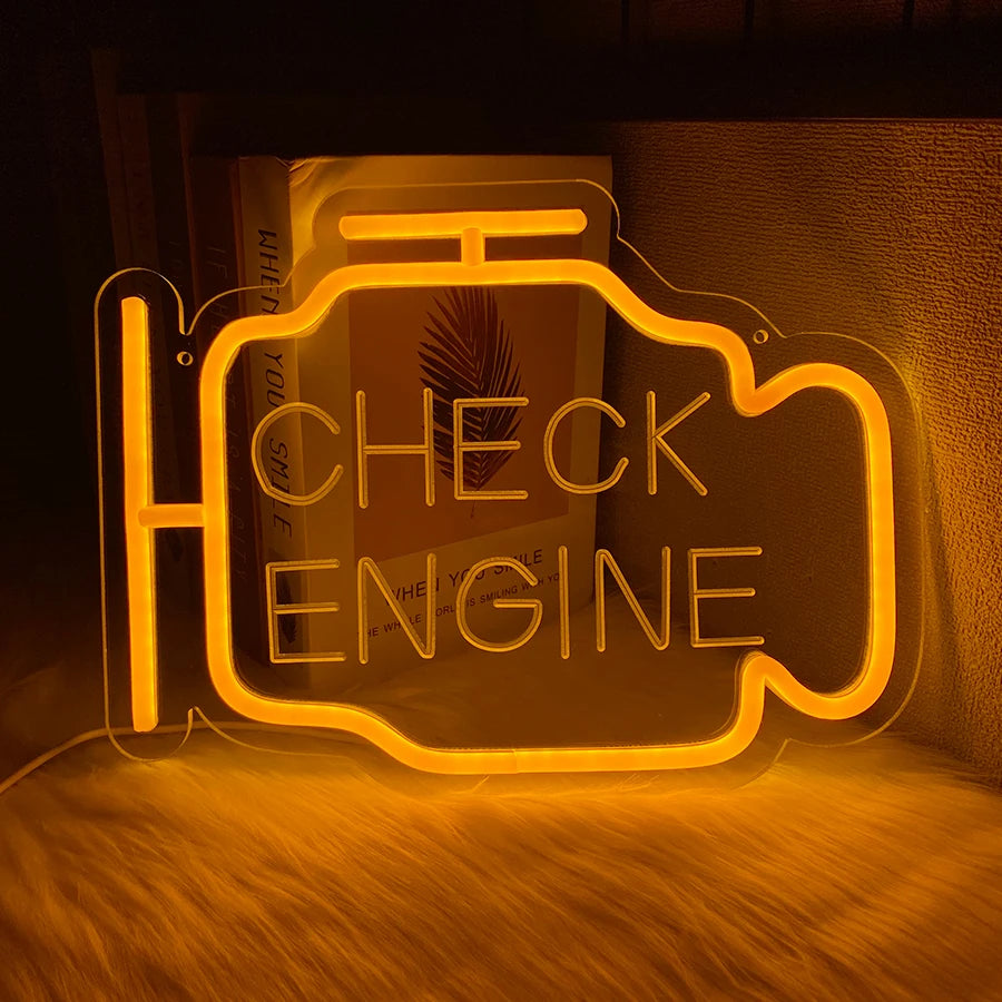 An oil change neon sign with the text CHECK THE ENGINE glowing orange on a dark background.
