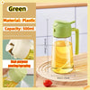 A green plastic oil spray bottle with a handle is shown next to a lemon slice on a wooden surface.