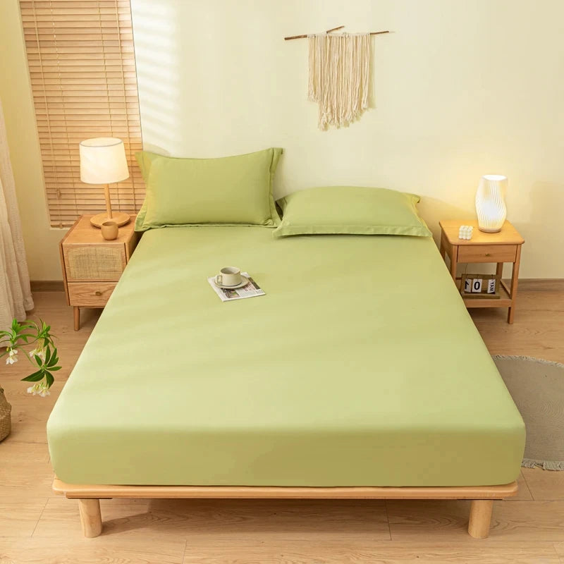 A light green fitted bed sheet set with matching pillowcases on a wooden bed frame in a bright room.
