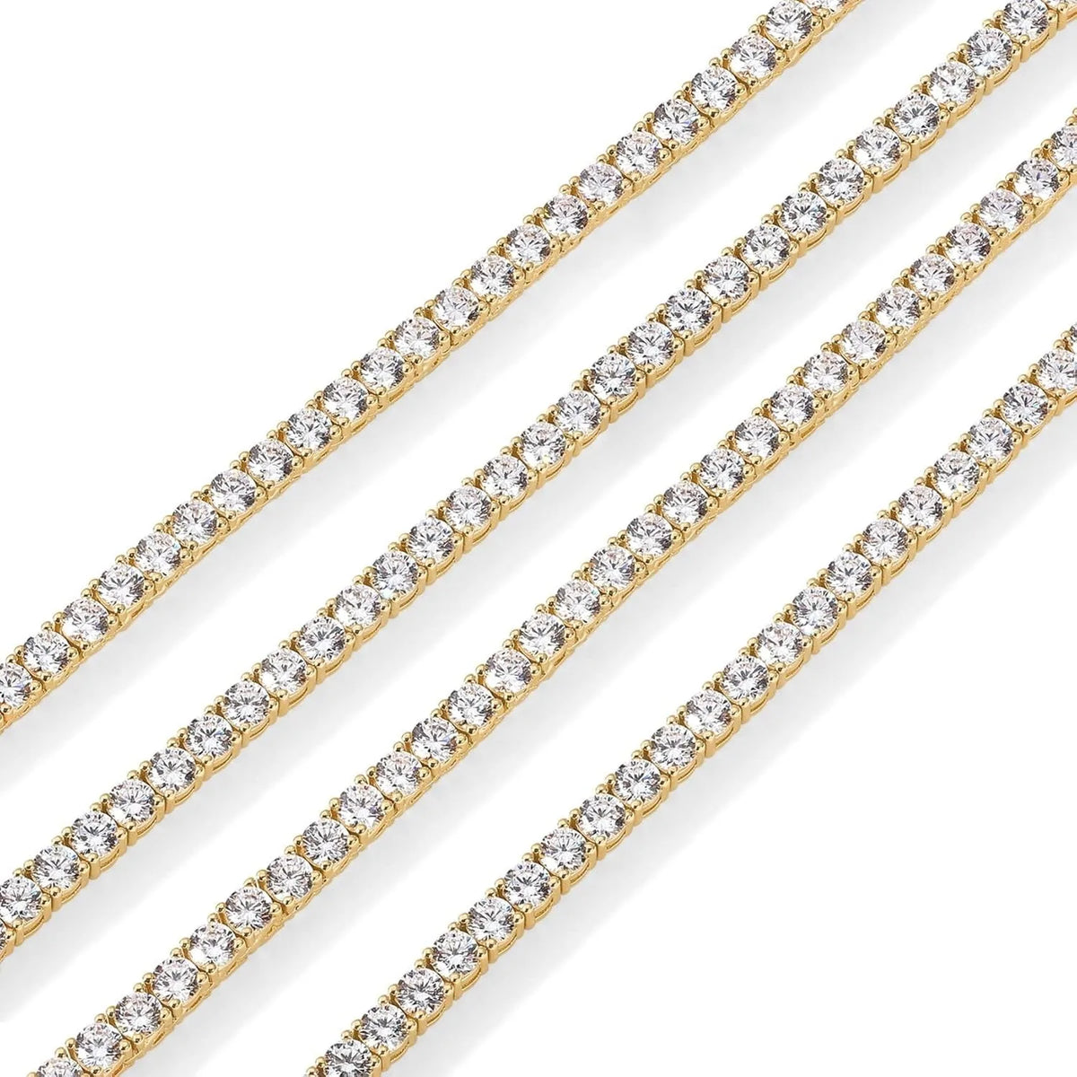 A close-up of a gold tennis necklace featuring numerous simulated diamonds, shown diagonally.