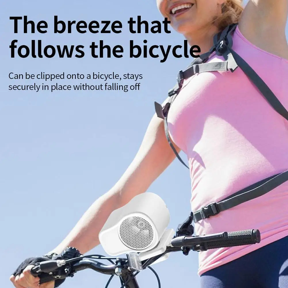 A woman is using a portable rechargeable clip-on fan attached to a bicycle, with the breeze following the cycle.