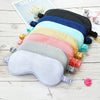 A stack of silk sleep masks in various pastel and dark colors laid on a white wooden surface.