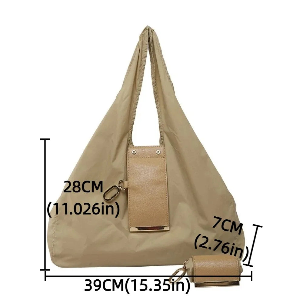 A beige retractable keychain tote bag folded into a compact pouch with an attached leather wallet.