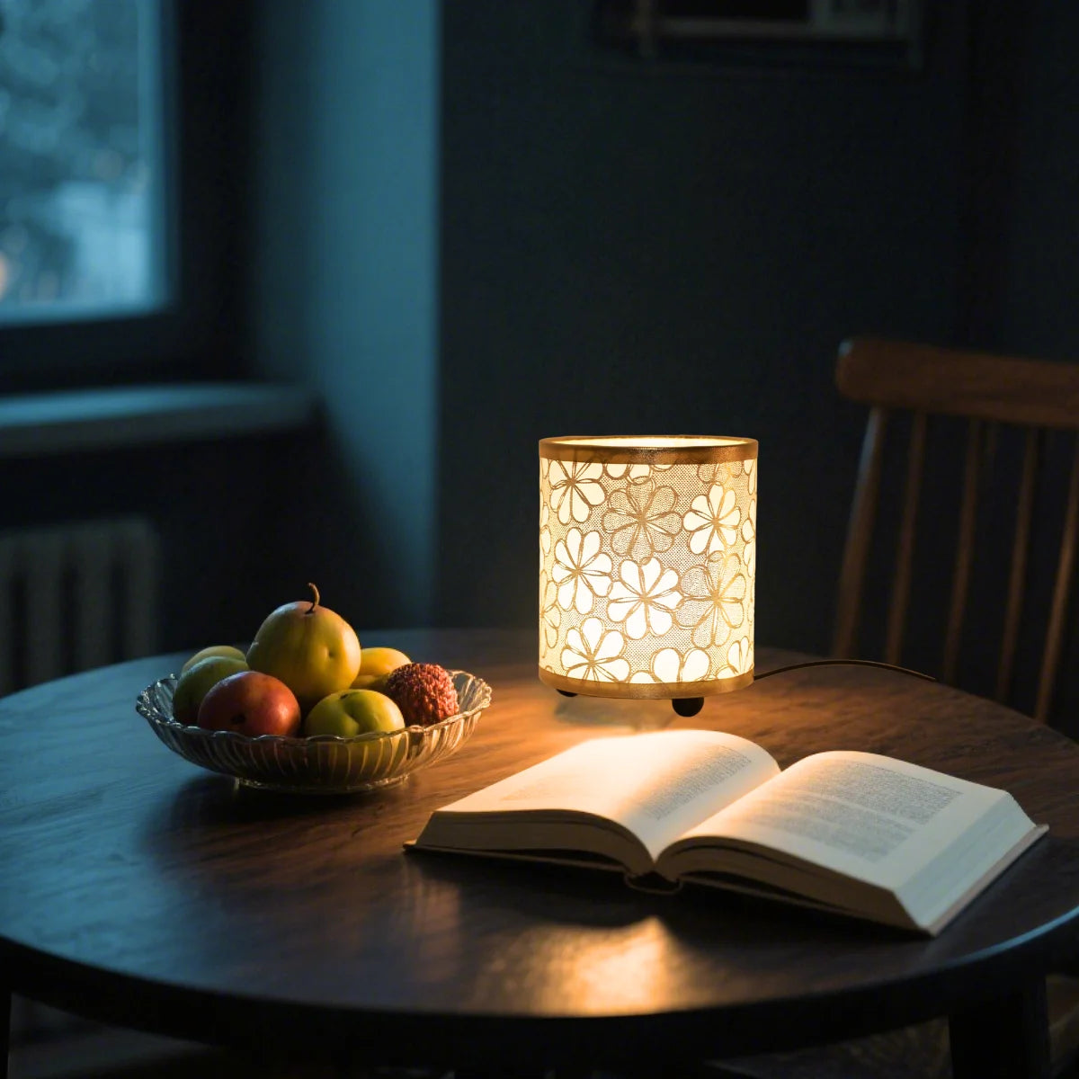 A printed fabric USB desk lamp with a warm glow illuminating an open book on a dark wooden table.