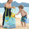 A woman and a boy on a beach holding a large mesh blue and green tote bag.
