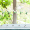 A row of lifelike dragonfly clips used for garden decoration displayed on a white surface.