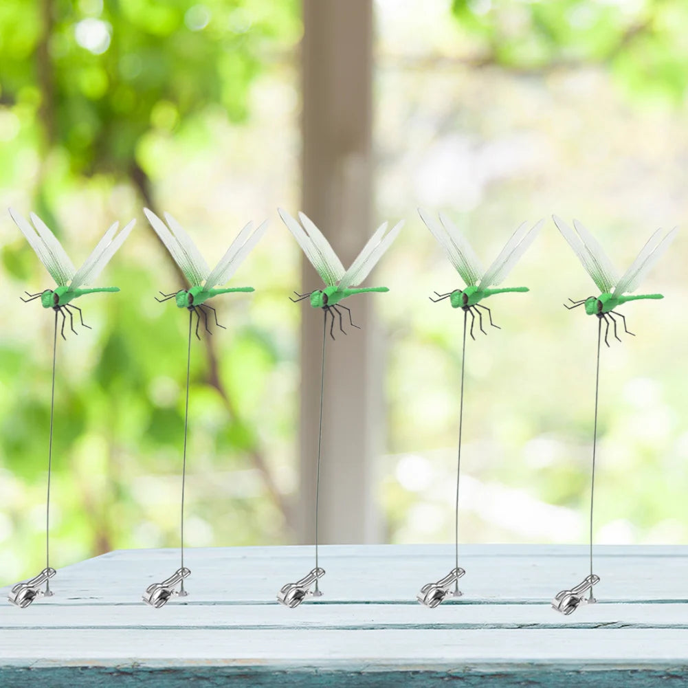 A row of lifelike dragonfly clips used for garden decoration displayed on a white surface.
