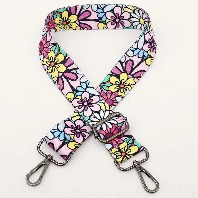 A pink and floral patterned fabric strap for an adjustable crossbody bag.