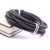 A coil of black braided leather cord with white ends resting on a light-colored surface.