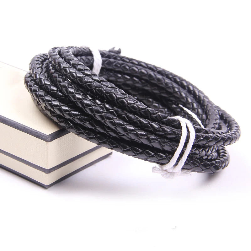 A coil of black braided leather cord with white ends resting on a light-colored surface.