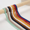 Macrame cord in various colors including blue, brown, red, yellow, and green is displayed on a wooden stick.