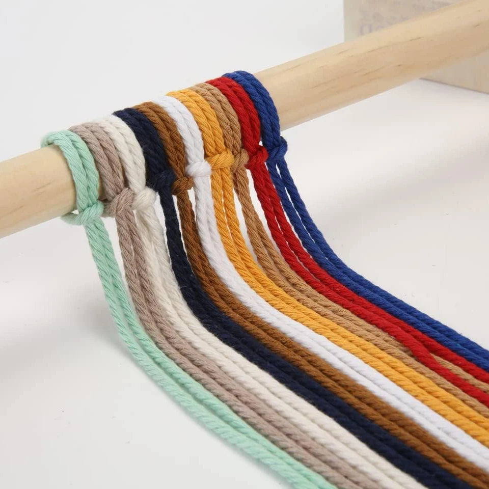 Macrame cord in various colors including blue, brown, red, yellow, and green is displayed on a wooden stick.