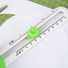 A white adjustable ruler or measuring tool is shown with a green circular component, placed on a white surface.