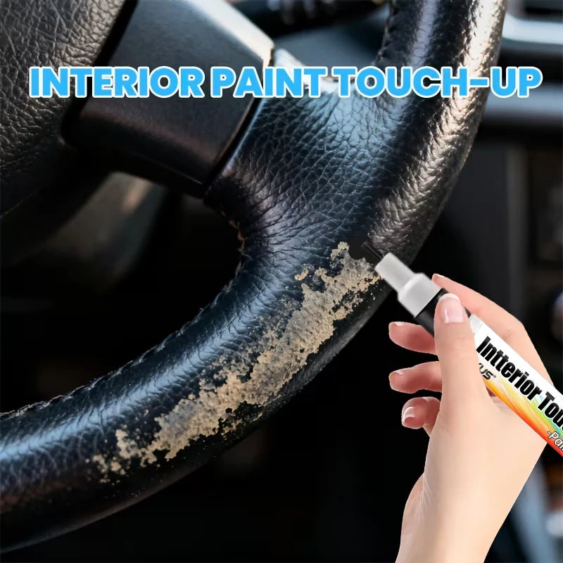 A hand applies interior paint touch-up to a car steering wheel using a precision pen.
