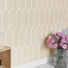 A beige wall with white arched tile molding and a vase of pink flowers.