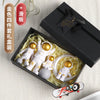 A set of four handcrafted astronaut figurine resin spaceman desk decor items in a black box with natural straw lining.