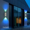 Exterior view of a modern building featuring wall-mounted rechargeable RGB motion sensor lights illuminating the facade.