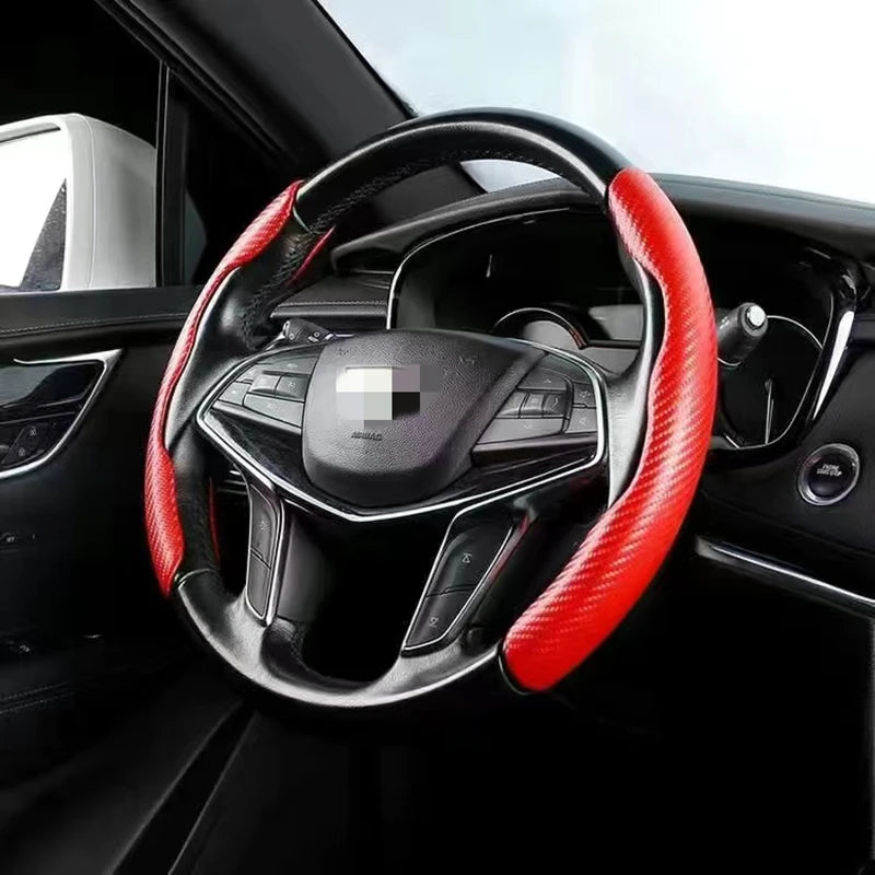 A close-up view of a black steering wheel with red carbon fiber accents inside a car interior.