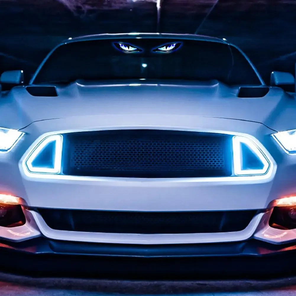 A white car's front grille features blue LED lights designed to look like demon eyes.