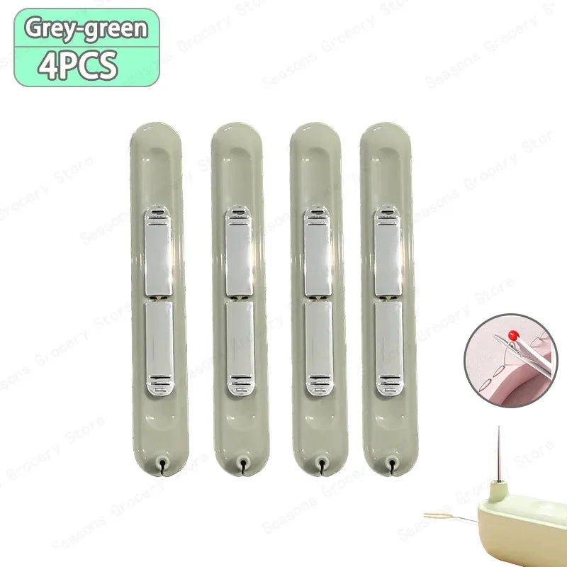 A set of four grey-green needle threader and seam ripper tools for sewing projects.