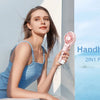 A woman holds a handheld fan with mist features in an outdoor setting.