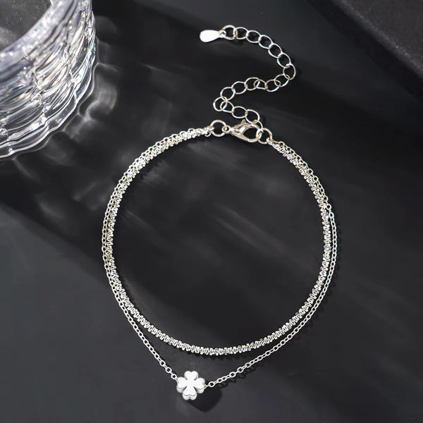 Un fragile bracelet d'orteil en argent, à design superposé et avec un petit charme floral.