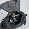 A gray vintage matte leather crossbody hobo bag with a zippered pocket revealing a black object.