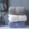 A stack of three bath towels in gray, white, and light blue shades on a white surface.